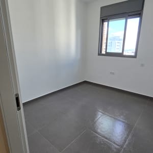 חדר עם קירות לבנים ורצפת אריחים אפורה