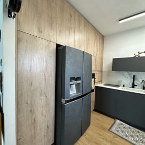 מטבח עם מקרר ודלתות עץ, כיור וברז שחור