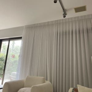 וילון לבן בסלון עם כורסאות ותאורה עליונה