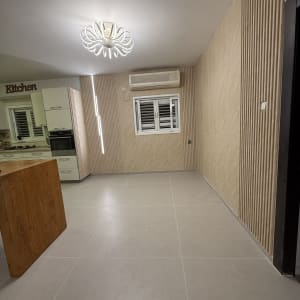 חדר עם רצפת פרקט, קיר מעוצב ותאורה מודרנית