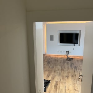 חדר עם רצפת עץ, טלוויזיה תלויה וחוטים חשמליים