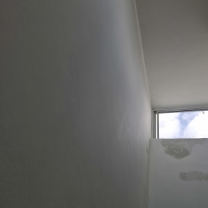 קיר לבן עם סימני תיקון צבע ליד חלון