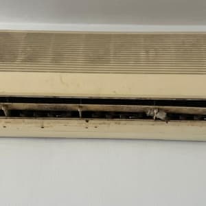 מזגן ישן ומלוכלך עם שלט על הקיר