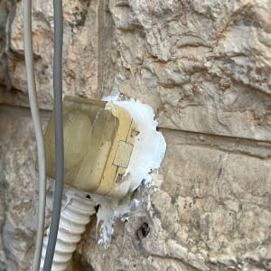 שקע חשמלי מותקן על קיר אבן עם חוטים