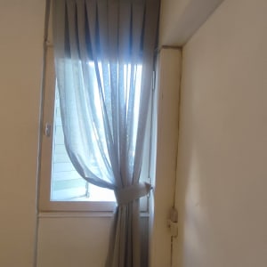 וילון אפור קשור ליד חלון פתוח