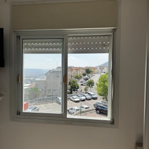 חלון פתוח עם נוף של חניה ובניינים
