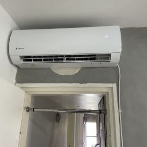 מזגן קיר לבן מותקן מעל דלת עם תצוגה דיגיטלית