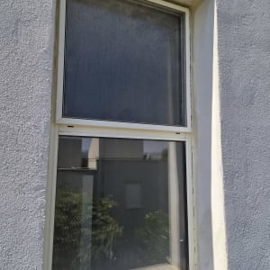 חלון עם מסגרת לבנה על קיר חיצוני אפור