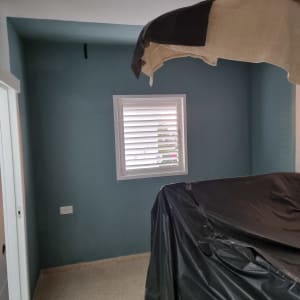 חדר צבוע בצבע כחול כהה עם חלון ותריסים