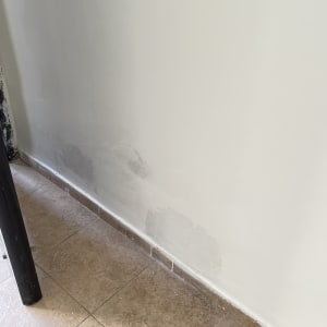 קיר צבוע עם תיקוני צבע על הרצפה