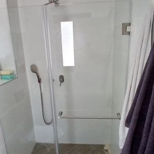 מקלחון זכוכית עם מגבות ותחתית עץ
