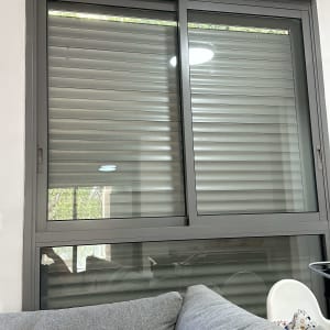 תריסים אפורים מותקנים על חלון גדול