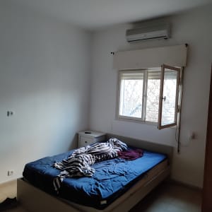 חדר שינה עם קירות לבנים ומיטה לא מסודרת