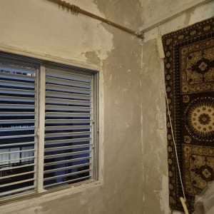 קיר עם טיח מתקלף וחלון עם תריסים