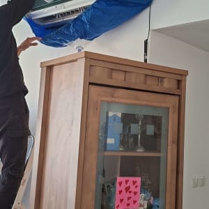 טכנאי מתקין מזגן על קיר עם כיסוי כחול