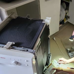 אדם מתקן מדיח כלים במטבח עם פנס ראש