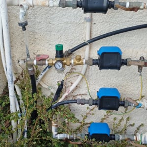 מערכת צינורות עם שסתומים ומד לחץ על קיר חיצוני