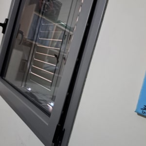 תריסים אפורים עם ידית שחורה על קיר לבן