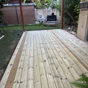 דק עץ חדש בגינה עם צמחייה מסביב