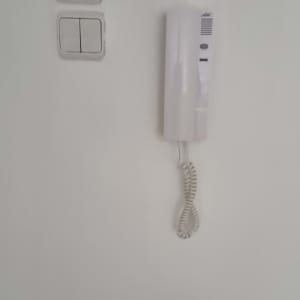 אינטרקום לבן עם שפופרת תלויה על הקיר