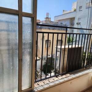 חלון עם מסגרת מתכת ומעקה ברזל שחור