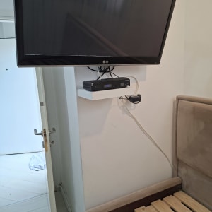 טלוויזיה מותקנת על קיר עם מדף וממיר