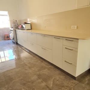 מטבח חדש עם ארונות לבנים ומשטח עבודה בהיר