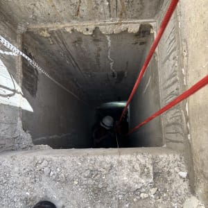 איש מקצוע מבצע עבודה בגלישת חבלים (סנפלינג) בתוך פיר בטון עמוק