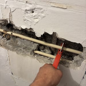 תיקון צינור בקיר עם כלי עבודה אדום
