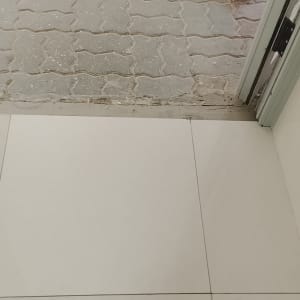סף דלת עם ריצוף פנים בהיר ואבנים משתלבות בחוץ