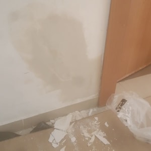 תיקון קיר עם טיח ושברי גבס על הרצפה