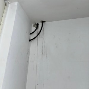 שני צינורות שחורים יוצאים מהקיר עם סימני נזילה