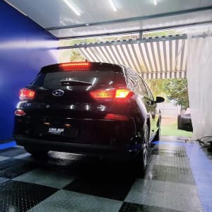 רכב שחור עם אורות דולקים בחדר שטיפה