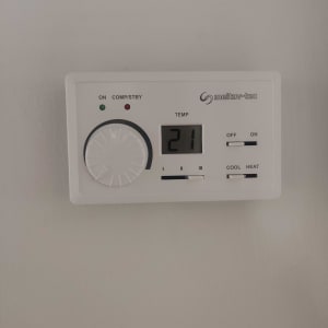 תרמוסטט מראה טמפרטורה 21 מעלות, כפתור וכפתורי הפעלה