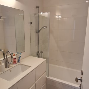 מקלחון זכוכית עם דלת זכוכית ליד אמבטיה