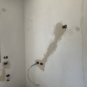 קיר עם חורים ותיקוני טיח, חוטי חשמל חשופים