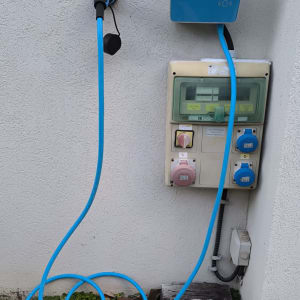 עמדת טעינה חשמלית עם כבלים כחולים על קיר חיצוני