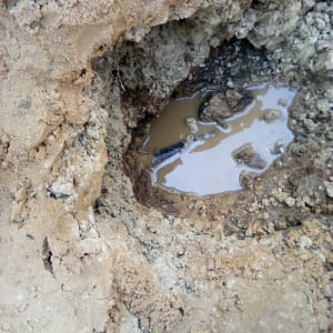 בור באדמה עם מים עומדים וצינור חשוף