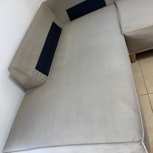 ספה אפורה עם כריות כהות על רצפת אריחים