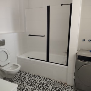 חדר אמבטיה עם מקלחון, שירותים ומכונת כביסה