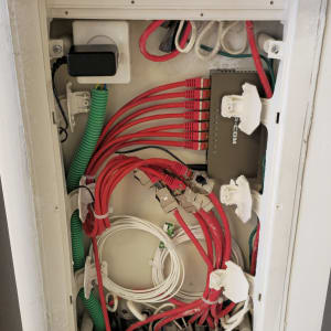 ארון תקשורת עם כבלים אדומים וירוקים, מחברים וציוד רשת