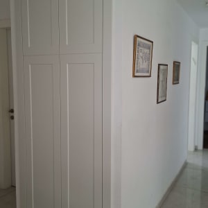 ארון כניסה לבן בנוי בנישה עם דלתות ציר וקרניז מעוצב