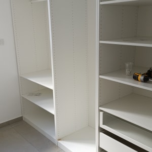 ארון לבן עם מדפים וכלי עבודה על המדף