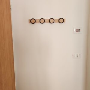 מתלה עץ עם ארבעה ווים עגולים על קיר לבן