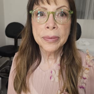 אישה עם משקפיים בחולצה ורודה עם פרחים