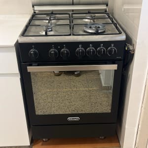 תנור גז שחור עם כפתורים ומבערים במטבח