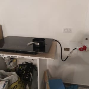 כבל חשמל מחובר לשקע בקיר ליד כיריים חשמליות