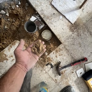 עבודת חפירה ותיקון צנרת עם כלים וחול על הרצפה