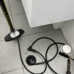 משאבת אוויר, צינור, פתח ניקוז, כלים על רצפה אפורה