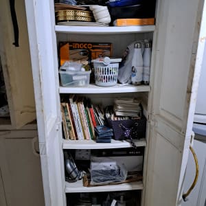 ארון עם מדפים מלאים בספרים, כלים ומכשירים חשמליים